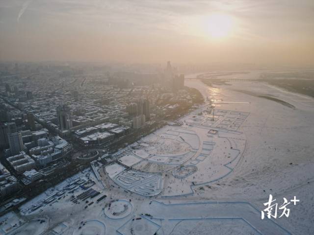 哈尔滨城区被冰雪覆盖，人们在结冰的松花江上游玩。